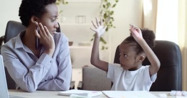 Portrait of african american woman with short hair sits at table at home or at school with her daughter student black child write draw with pens and markers on paper in notebook communicate talk speak