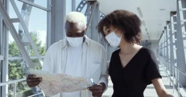 Etnik Afro-Amerikan turist çiftleri yabancı öğrenciler. Medya maskeli yeni evliler yeni şehir ülkesine geldiler. Haritaya baktılar ve Coronavirus sırasında doğru yol, seyahat konsepti aradılar.