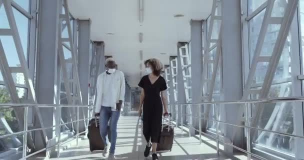 Full-length footage african american couple friends colleagues in medical masks and with suitcases walk through airport terminal station to land plane arrive on business trip travel during pandemic — Stock Video