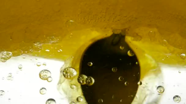 L'olio di girasole giallo è mescolato con acqua, non si dissolve. Le lampadine a bolle d'aria galleggiano nei liquidi creando fantasie, texture e sfondi. Colpo al rallentatore del liquido dell'olio da versare. Vitamina E sana — Video Stock