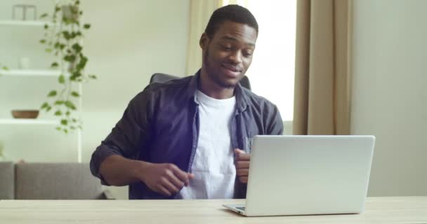 若いですハンサムな笑顔ハンサムなハンサムなアフロアメリカのビジネスマン学生フリーランスノートパソコンのウェブカメラに話してオンライン会議のチャットでビデオ通話に応答,隔離中のリモート通信コンセプト — ストック動画