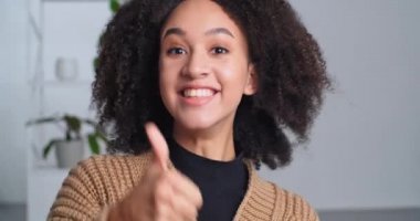 Gülümseyen Afro-Amerikan melez genç kızın portresi. Kameraya olumlu bir jest, beğeni ve onaylama ifadesi gösteren samimi bir genç kız. Etnik bayan geniş dişli gülümsemeyi sever.