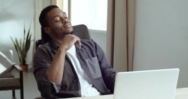 Yorgun afro-amerikalı iş adamı iş yerinde dizüstü bilgisayarın önünde oturuyor stresten gözleri kapanıyor sıkı çalıştıktan sonra dinleniyor dinleniyor gelecek planlarını düşünerek dinleniyor.