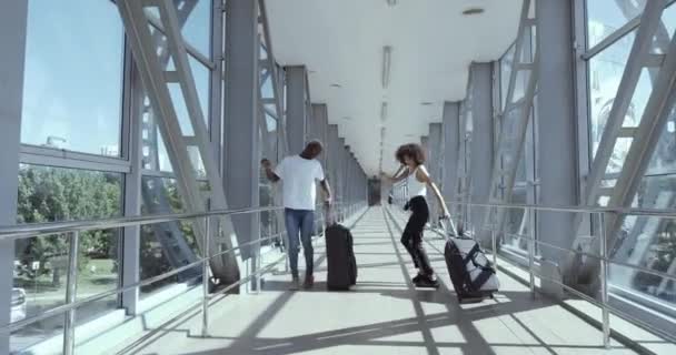 Etnisch koppel twee mensen broer en zus vrienden tieners in witte t-shirts van Afrikaanse etniciteit millennials hebben plezier dansen met koffers in luchthaven terminal gevoel geluk van reizen — Stockvideo