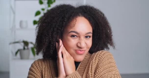 Portrait of flirtatious beautiful young adult African American woman mixed race female teenager model folds hands palms body parts near female face head looks at camera grimaces blowing lips close-up — Stock Video