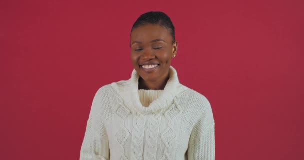 Studio shooting afro american woman ethnic girl model brunette mixed race lady wears white sweater waving hello while saying bye greet souriant friendly looking at camera standing on red background — Video