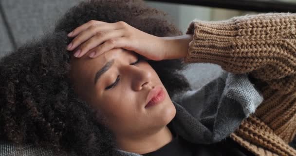Großaufnahme weibliches Gesicht runzelt die Stirn, Afroamerikanerin leidet an Schnupfen Fieber hält sich an der Hand leitfähige Stirn Kopf fühlt Kopfschmerzen misst Temperatur mit Thermometer — Stockvideo