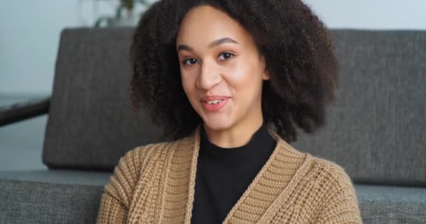 Vista desde la webcam Afro mujer americana habla en la cámara respuestas videollamada se sienta en casa en la sala de estar se comunica con el maestro para estudiar de forma remota durante el coronavirus, estudiante chica dispara vídeo para vlog — Vídeos de Stock