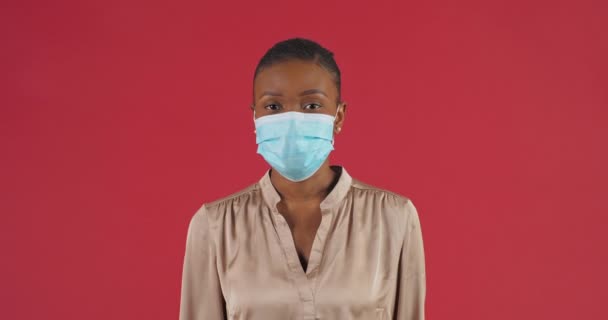 Молода афроамериканська жінка у білій бавовняній вірусній масках, тримаючи за руку перед собою як стоп-жест, що забороняє наближатися до ізольованих. Коронавірус covid-19 запобігання епідемії — стокове відео