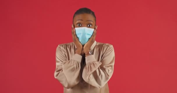 Studioporträt schockiert afroamerikanische Mädchen ethnische Millennial Frau junge schöne Patientin in medizinischer Maske steht posiert Gefühl Erstaunen Angst Überraschung hält seinen Kopf mit den Händen in Angst — Stockvideo