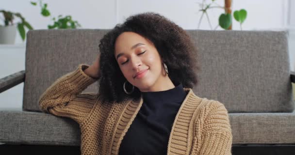 Portret afro amerykańska spokojna kobieta odpoczywa relaksuje się w przytulnym salonie opierając rękę na nowej kanapie, etniczne dziewczyny właściciel domu korzystających dom kupił mieszkanie, sukces leniwy pani siedzi z zamkniętymi oczami — Wideo stockowe