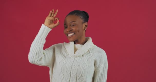 Porträtt av afro amerikansk kvinna modell framgångsrik etnisk dam visar hand gest okej symbol för seger bra jobb triumf rekommendation stöd tittar på kameran ler isolerad på röd bakgrund — Stockvideo