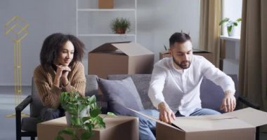 Afro-Amerikalı kadın, eş kız arkadaş ve beyaz, kendine güvenen yakışıklı koca koca koca koltukta oturuyor, karton kutuları açıyor paketleri açıyor, yemek siparişi veriyor, beyaz vazo sevindiriyor.