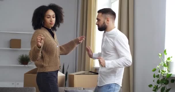 Casal amigos família multinacional afro-americano mulher e caucasiano homem dançando cercado por caixas de papelão regozijo movimento comemorando nova fase da vida coletando coisas que gostam de se mover para a música — Vídeo de Stock