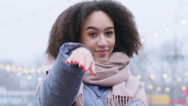 Close-up afro americana hermosa chica bailando al aire libre, adolescente con rizos celebrando vacaciones de invierno hace movimientos rítmicos con sus manos a la música mira a la cámara risas y sonrisas sinceramente — Vídeos de Stock