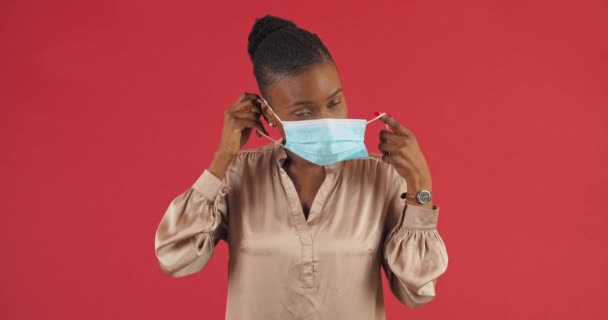 Estúdio feminino retrato afro-americano positivo mulher etnia menina paciente vestindo máscara cirúrgica médica no rosto mostra polegares para cima coloca como aprovação gesto apoio consentimento recomenda o uso de respiradores — Vídeo de Stock