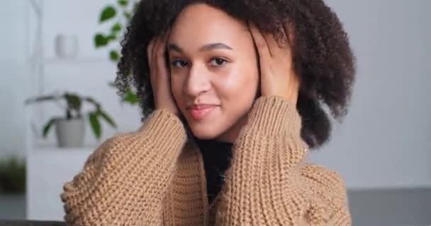Portrait of a female face with perfect dark skin and natural makeup, african woman straightens curly hair and touches head with hands blows air kiss to beloved boyfriend seductively looking at camera — Stock Video