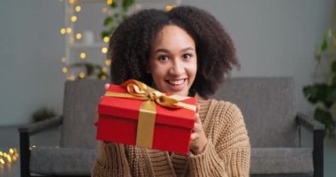 Web kamerası Afro-Amerikan Etnik Kadın Etnik Kız 'dan ev kayıtları videosundan büyük bir sohbet konferansında kırmızı hediye kutusu gülümsemesi ve tatil konseptini gösteriyor.