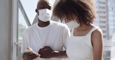 Tıbbi maskeli iki kişinin portresi, birkaç Afro-Amerikalı genç kız ve zenci erkek hipster sohbet ederek zaman geçiriyorlar cep telefonu kamerasında fotoğraf çekiyorlar, karantina sırasında sevişiyorlar.