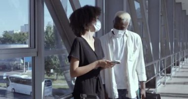 Afro-Amerikalı çift havaalanında durup uçak biletleri tutarak Coronavirus 'a karşı koruyucu maskeler takarak balayı için yurt dışına gitmeyi bekliyor.