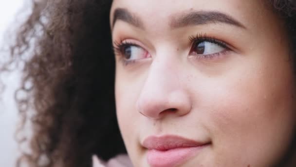 Close-up female human face with clean dark skin, cosmetology dermatology concept. Portrait of afro american girl with curls with long eyelashes and black eyebrows light lipstick perfect makeup smiling — Stock Video