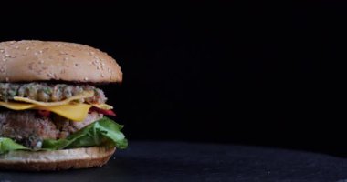 Yakın plan sarı, yağlı, sağlıksız patates kızartması iştah açıcı, büyük hamburger, sağlıksız çörek, kafeterya barında siyah masanın üzerine uzanmış patates kızartması, Amerikan fast food konsepti.