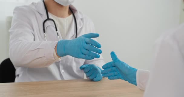 Закрыть ладони человека два врача в защитных латексных перчатках пожимая руки после совместной работы в больнице хирургии на успешной операции. Медицинские коллеги здороваются друг с другом — стоковое видео