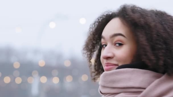 Portret van Afrikaans Amerikaans jong meisje donkere huid dame met krullend afro kapsel draagt roze warme sjaal in de winter koud weer staat alleen buiten uitademen stoom lachende tanden kijken naar de camera — Stockvideo