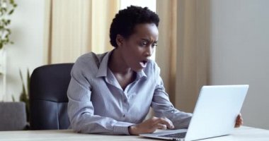 Stresli Afro-Amerikan kadını evinde ya da ofisinde oturmuş dizüstü bilgisayara bakarken kötü hissediyor, şaşırmış etnik kız bilgisayar okuyarak inanılmaz haberler veriyor.
