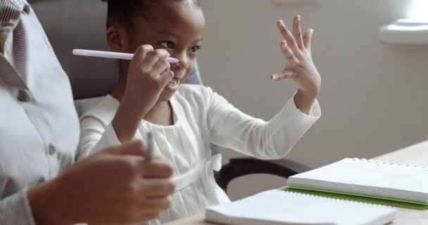 Κοντινό πλάνο γυναίκα και το παιδί κάνει την εργασία μαζί γράφοντας στο σημειωματάριο με στυλό μετρώντας στα δάχτυλα μαθαίνοντας μαθηματικά, νεαρός εραστής μαμά βοηθώντας το κορίτσι προσχολικής ηλικίας αφροαμερικάνικο μωρό, έννοια της κατ 'οίκον εκπαίδευσης — Αρχείο Βίντεο