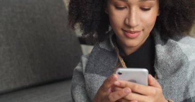 Güzel, eğlenceli, pozitif, koyu tenli Afro-Amerikalı bir kızın yakın portresi. Telefondan el ele tutuşun. Mobil cihaz sohbeti ekranına bakın.