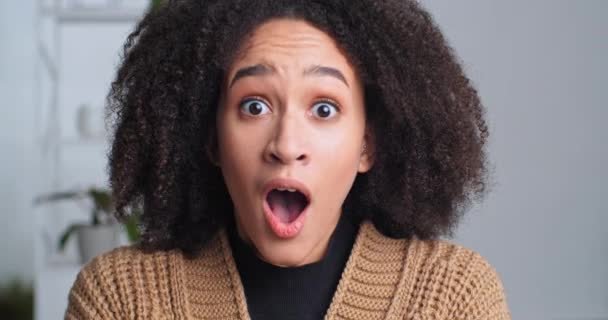 Close-up chokeret kvindelig ansigt, overrasket reaktion, afro amerikansk krøllet pige hørte fantastiske uventede nyheder åbner munden fra stress frygt entusiastisk holdinghoved med hænder, overraskelseskoncept – Stock-video
