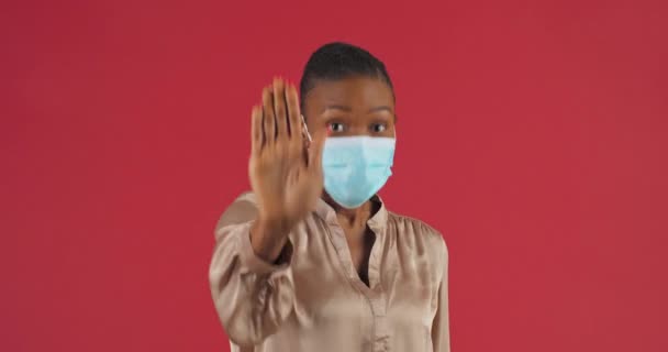 Sluit het handstopbord. Blijf weg symbool. Afro-Amerikaanse vrouw draagt steriele medische masker toont gebaar van afstand voor coronavirus uitbraak lock down, maakt beperking zet palm voor haar — Stockvideo