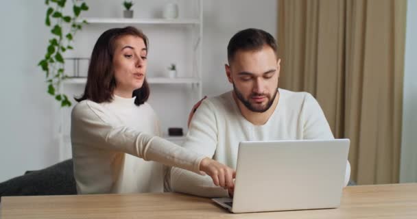 Junge kaukasische Paar verbringen Wochenende zu Hause im Wohnzimmer mit Laptop Websurfen Möbel suchen diskutieren Kauf machen Lebensmittel online bestellen, genießen Sie Komfort Online-Einkauf auf E-Commerce-Dienstleistungen — Stockvideo