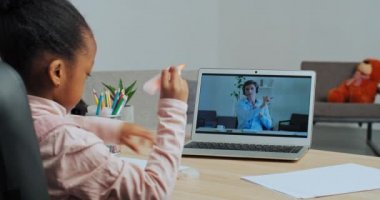 Yetenekli Afro-Amerikan öğrenci ekrandaki öğretmenine bakıyor erkek hocasının tavsiyelerini dinliyor dizüstü bilgisayar programlarında resim çiziyor web kameraları çevrimiçi video dersini izliyor.