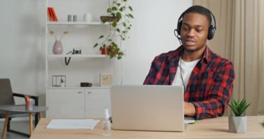 Kulaklıklı Afro-Amerikalı iş adamı yönetici bilgisayarlı kamerayla konuşuyor. İş arkadaşlarıyla ya da patronuyla web konferansı yapıyor. Tecrit süresince ana ofisten proje görevleri ve konsültasyonları tartışıyor.