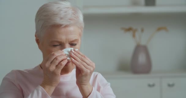 Portret ongezonde oudere oude vrouw volwassen dame die lijdt aan loopneus met behulp van papieren weefsels zittend op bank koude seizoen ziekten of respiratoire virus rhinitis allergie symptomen, gezondheidszorg concept — Stockvideo