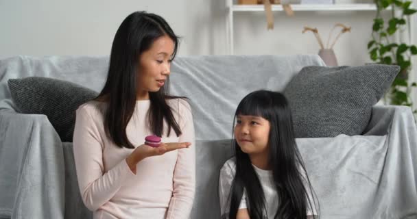 Asiatisk familie hjemme, ung koreansk mor holder hjemmelavede cookies bagt varer slik i hånden lille pige vegetarisk datter rådgiver at spise frugt viser mor grøn frisk æblefrugt, kost koncept – Stock-video