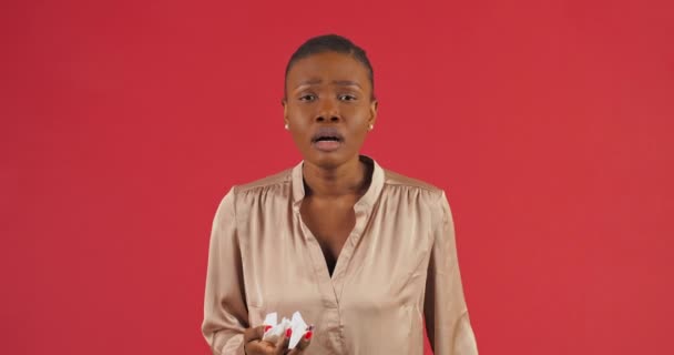 Afro american sick girl stands posing on red background in studio suffers from runny nose allergic reaction of seasonal renitis wipes nose with handkerchief sick with respiratory virus sneeze sniffs — Stock Video