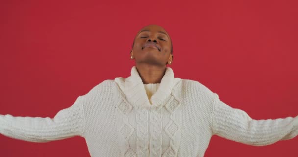 Joven chica africana bonita modelo étnico con suéter casual blanco cogido de la mano en el gesto de yoga relajante meditando tratando de calmarse haciendo buenos ejercicios aislados en el fondo de color rojo en el estudio — Vídeo de stock