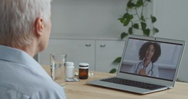 Yaşlı hasta kadın hasta büyükannenin bilgisayardan doktora yaptığı görüntüye bakın. İnternetteki terapist kadın uzman konferansı ile görüntülü konuşma, tecrit sırasında uzaktan muayene.