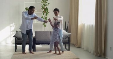 Mutlu Afrika etnik kökeni baba ve anne eğleniyor küçük anaokulu çocuğuna evde modern oturma odasında dans etmeyi öğretiyor. Baba ve anne ve kızı eğlenceli aktiviteler yapıyorlar. Hafta sonları boş zamanların tadını çıkarıyorlar.