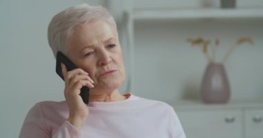 Yaşlı kadın, gri saçlı yaşlı kadın, çocuklara cep telefonuyla konuşuyor ve torunları da internetten yemek siparişi vermek için kablosuz cihaz akıllı telefonu kullanıyor ya da evden alışveriş haberleri paylaşıyor.