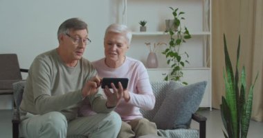 Kafkasyalı yaşlı bir çift, gözlüklü yaşlı bir adam ve olgun bir kadın koca ve büyük anne ve büyük baba, torunları ve çocuklarıyla iletişim kurmak için cep telefonu kullanıyor.