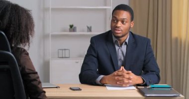 Resmi takım elbiseli Afro-Amerikalı iş adamı, modern bilişim pazarlama şirketinde röportaj yapıyor. Toplantı ofisinde otururken kadın patrona mesleki becerilerden bahseden özgeçmişini gösteriyor.