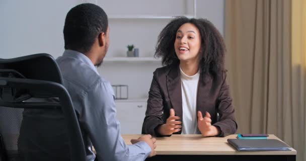Невпізнаваний бізнесмен африканського походження, який сидить у сучасному офісі, спілкується з діловою жінкою, яка пропонує проект, обговорюючи можливості, даючи п "ять з жестом спільної роботи. — стокове відео
