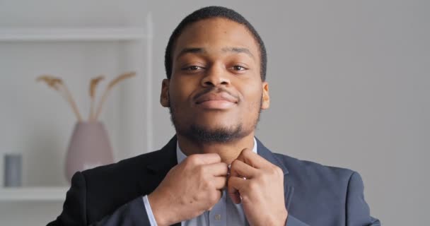 Portretul afro-american încrezător om de afaceri elegant tip etnic mire se pregătește pentru întâlnire de nuntă în birou poartă costum negru eligibil scump și butonul cămașă albastră în sus guler uitându-se la camera foto — Videoclip de stoc