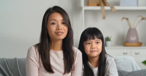 Portret web camera bekijken vrouw moeder ouder zus en klein meisje kind etnisch aziatisch koreaans familie twee brunettes zitten thuis op bank zwaaien groet handen praten maken video oproep online chat — Stockvideo