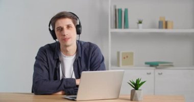 Sakin iş adamı serbest çalışan beyaz erkek milenyum öğrencisi iş yerinde masa başında oturmuş dizüstü bilgisayarda modern online oynatıcı kullanarak müzik dinleyerek favori melodiyi dinliyor.
