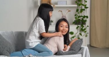 Asyalı genç ve sevgi dolu anne kanepede yatar. Aktif, zıplayan küçük kızını sırtında taşır. Şakacı kız, hafta sonları modern oturma odasında küçük çocukla vakit geçirir.